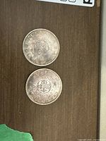 Two 1964 Charlottetown Quebec silver dollar coins showing both sides arranged on a brown surface.