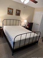 Black metal bed frame with mattress on it, showing headboard and footboard in a bedroom setting