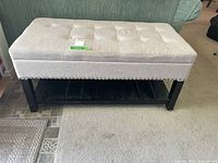 Top view of rectangular beige button-tufted upholstered storage bench with dark wood frame and lower slatted shelf underneath.