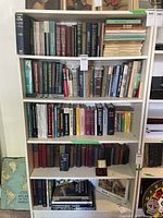 Front view of the filled white bookcase showing multiple shelves laden with various books, illustrating shelf capacity and general appearance.