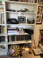 Front view of white MDF bookcase filled with various items including books, boxes, and decorations to show shelving and dimensions.