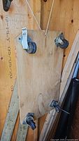 Bottom view of wooden cart showing four swivel caster wheels mounted on plywood platform.