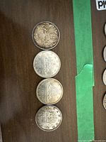 Four Canadian silver dollar coins laid out, showing both obverse and reverse sides with visible dates 1956 and 1966.