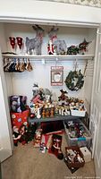 Photo showing large reindeer figures, indoor lights, Precious Moments nativity figures, Santa figurines, wreath, and assorted ornaments and bins below.