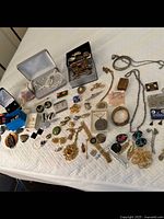 Overview of assorted costume jewelry laid out including necklaces, earrings, brooches, bracelets, and watch.
