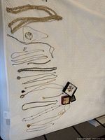 Overview of all costume jewelry items spread on a white textured surface showing necklaces, earrings, and brooches.