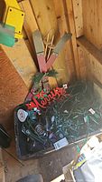 Bin filled with various Christmas lights, cables, and wooden ski decoration with Merry Christmas sign