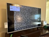 Front view of the LG 43 inch TV powered on showing static test screen.