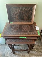 Photo showing stacked three wood nesting tables with carved tops and serving tray on top