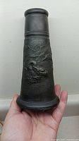 Front view of the black ceramic vase with raised dragon design and textured surface showing detail and shape.