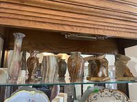 Front view of shelf displaying six onyx vases of different shapes and sizes.