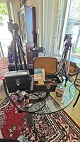 Photo showing full lot including Pentax camera, tripods, cases, light meter, slide viewer, and accessories on glass table and carpeted room.