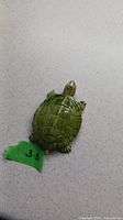 Top-down photo of green painted porcelain turtle figurine showing shell and feet details, with a green tape label '3.5' indicating length measurement.