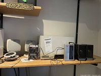 Shelf with various speakers and radio units including Altec Lansing speakers, Budweiser mini speaker and others.