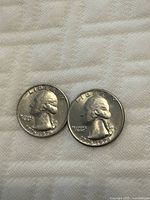 Obverse side of two 1976 US Bicentennial quarters showing George Washington profile, one coin without mint mark, one with mint mark.