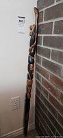 Full view of hand-carved wooden walking stick showing carved animal head handle and snake motif along shaft.