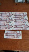 Seven 1986 Canadian 2 dollar bills showing front side with Queen Elizabeth II portrait.