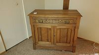 Front view of solid wood antique cabinet showing wood grain, drawer, and double door panels.