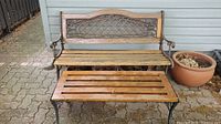 Front view of outdoor bench and matching table on patio with decorative metal framework and wooden slats, showing overall condition and dimensions.