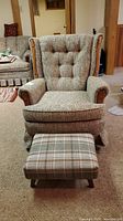 Front view of swivel rocker chair with cushioned back and matching plaid ottoman.