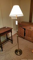 Full view of the lamp showing the shade, adjustable arm, and base with furniture background.