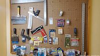 Wide shot of assorted hand tools and hardware accessories pinned on pegboard