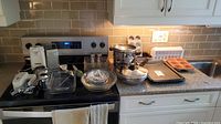 Overview of various kitchen items on stove and counter including cookware, baking dishes, muffin tin, and cookie sheets