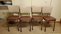 Four MCM chairs lined up against wall on carpet floor, showing overall condition and design