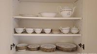 Full view of shelves showing 8 cups, saucers, multiple plates, bowls, platters and teapot.