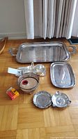 Complete set of silverplate items on floor including trays, covered dish, wine drip, ashtray, and cup.