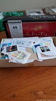 Box filled with assorted cancelled postage stamps visible on torn envelopes and paper scraps.