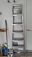 Full view of the aluminum step ladder showing 5 steps and metal top platform with some paint residue.