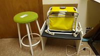 Photo showing green cushioned stool, small bench with black seat and yellow folding stool with storage on top