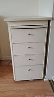 Front view of white storage dresser showing four drawers and metal knobs