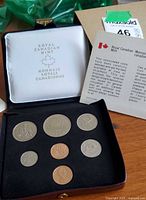 Photo of open black presentation case showing seven uncirculated 1977 Canadian coins in black velvet lining with informational insert and Royal Canadian Mint logo inside lid.