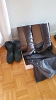 Photo showing two pairs of women's winter boots. The brown knee-high boots are in their box with black tissue paper, and the black insulated boots stand beside it.