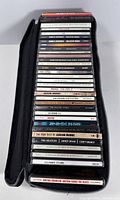 All 30 CD jewel cases stacked inside zippered carrying case