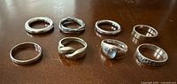 Group shot of 8 silver rings on tabletop