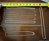 Overview of eight sterling silver chains laid under measuring tape