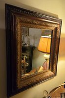View of the antique Edwardian George V style mirror showing its ornate multi-frame structure and gilded decorative carvings under warm lighting.