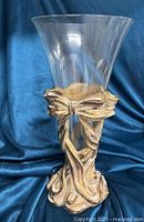 Photo of gilt metal Art Nouveau Revival style vase holder with clear flared glass cone insert against blue fabric background.