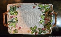 Top view of rectangular serving dish showing detailed berry and floral decorations with basket weave texture and handles.