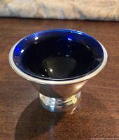 Photo of a small Birks mint dish showing the polished silver-toned exterior and deep blue glass liner inside.