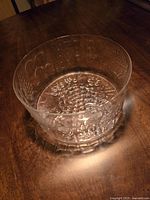 Top angled view of a round clear embossed glass bowl showing textured raised dot patterns on the glass surface and the high, flared collar edge.