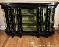 Front view of the ebony china cabinet showing black wood with glass doors, decorative brass accents, and fluted columns.