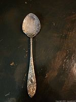 Repousse jam spoon with intricate floral and leaf pattern on handle and bowl, showing vintage craftsmanship details.