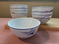 Eight ceramic bowls in two stacks of four each, showing the blue brush stroke design on white ceramic surface.