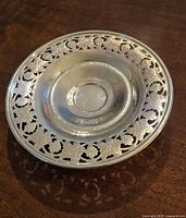 Top view showing intricate pierced grapevine and leaf patterns around the rim and embossed grapevine motifs on the solid center.