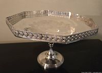 Side view of the silver plated cookie comport showing its octagonal shape, pedestal base, gallery edge, and engraved center pattern.
