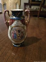 Photo of a 6-inch handpainted porcelain vase with dual handles and detailed classical figure artwork, marked Austria, circa 1920s.